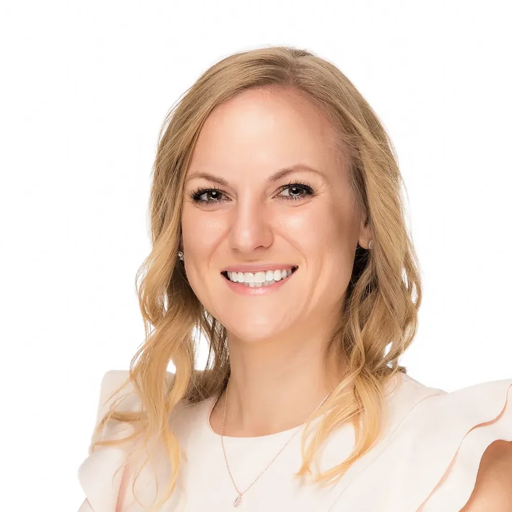 Headshot of a blonde woman in a pink ruffled top on a white backdrop