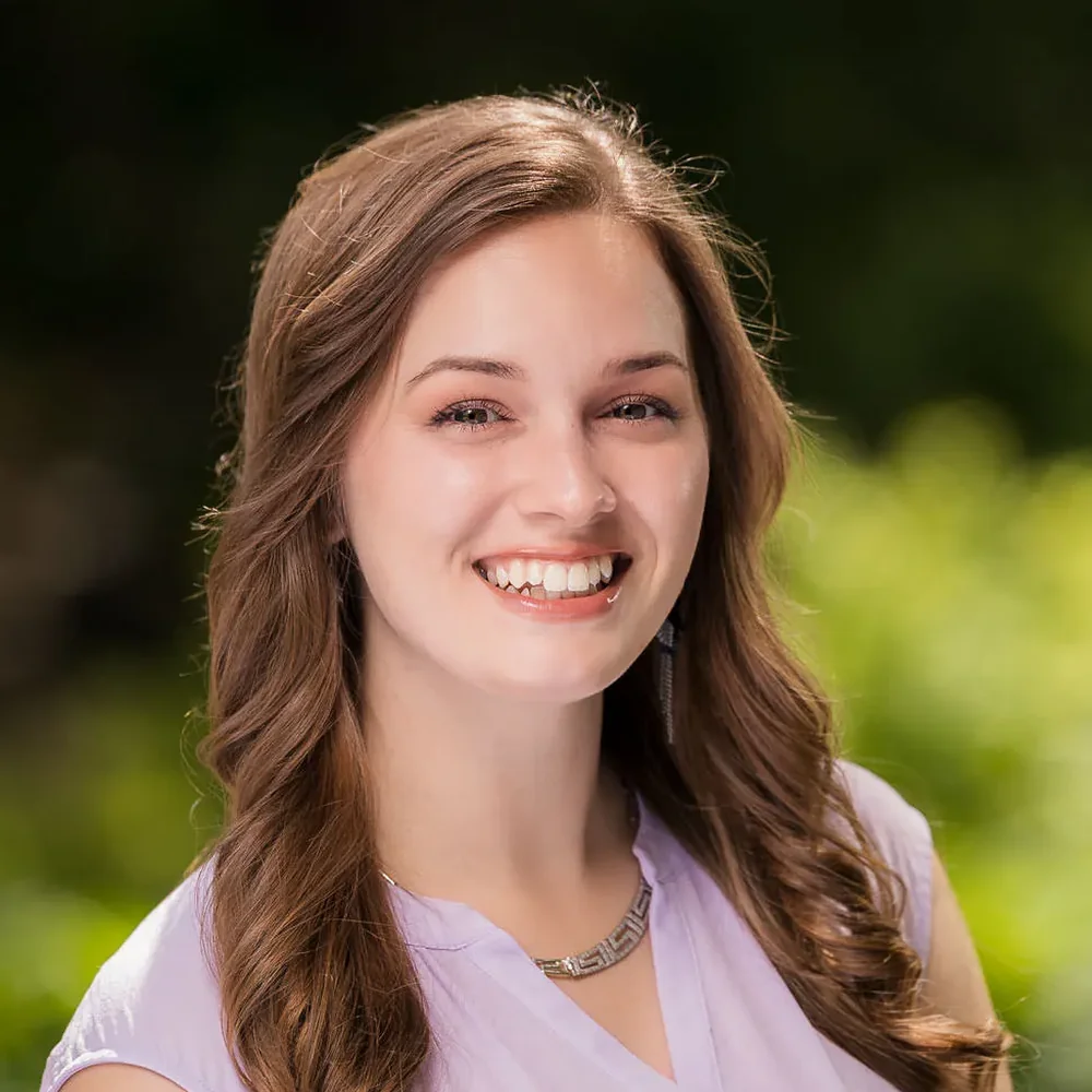 Outdoor individual headshot of a young woman in a lavender top