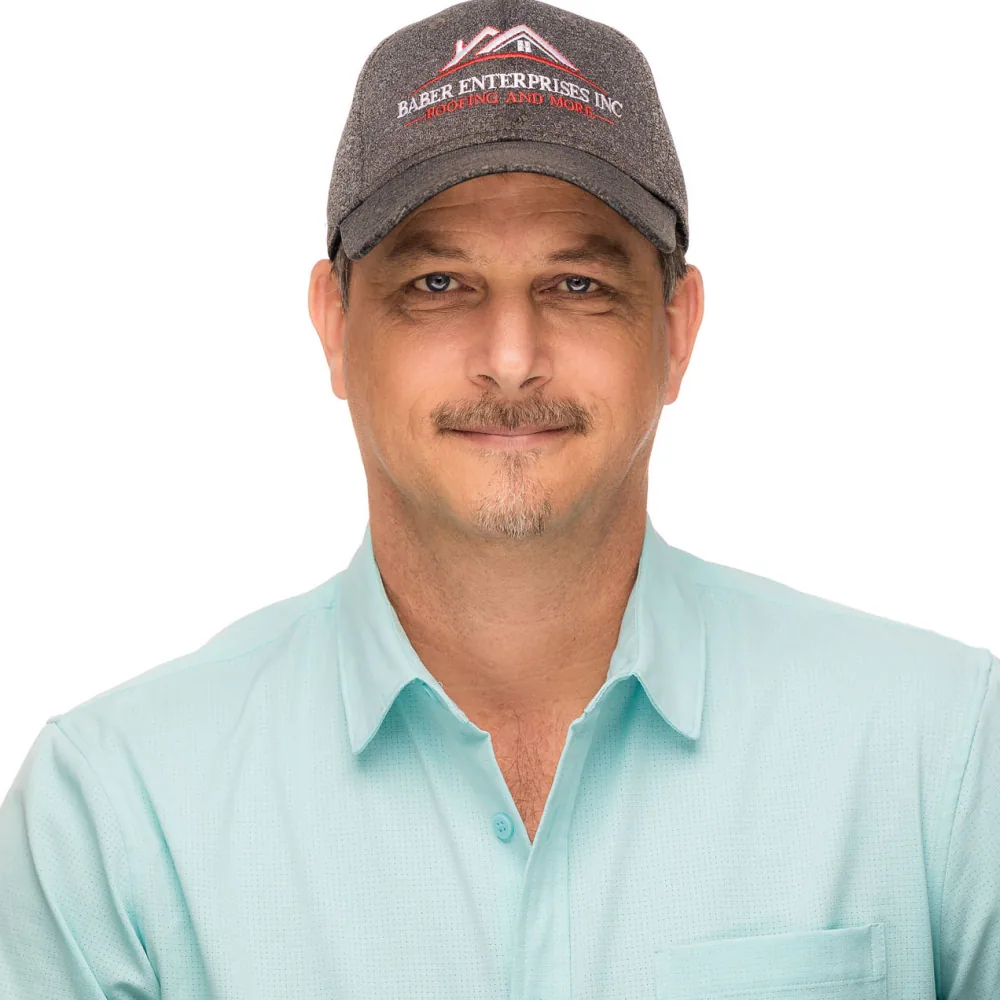 Studio headshot of a man in a ball cap and mint green polo on a white backdrop