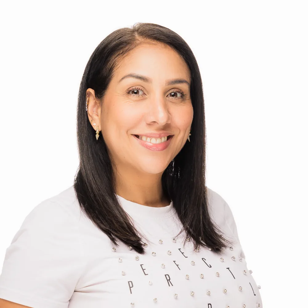 Studio headshot of a woman with dark hair in a white tee on a white backdrop