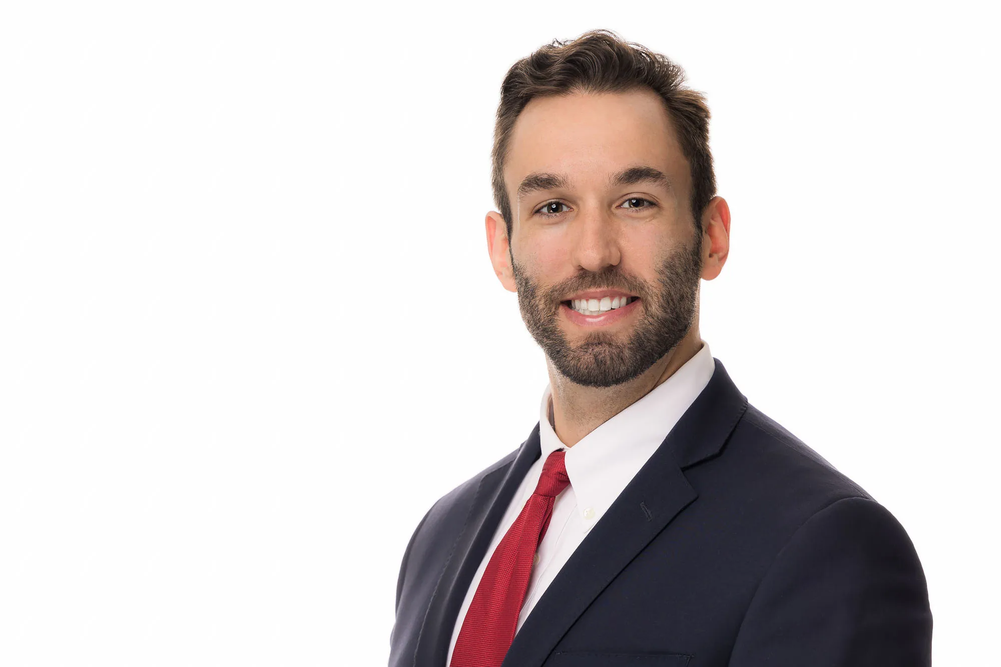 Male executive in navy suit and red tie, professional headshot on white backdrop